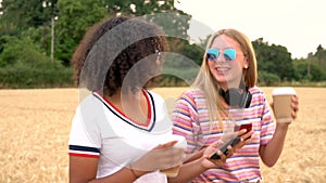 Teen young women wearing sunglasses drinking coffee and taking selfies on their smart phones