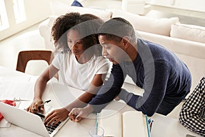 Teenage African American  girl doing homework with help from her dad, looking at computer screen, elevated view