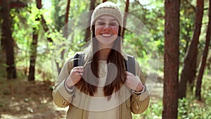 Teenage American girl young woman hiking with backpack in forest woodland. Video portrait of hiking teenager girl. Sport healthy c