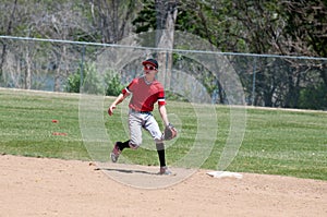 Teenage baseball shortstop running on field.