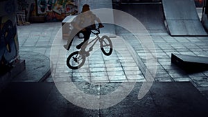 Teenage bmx rider performing dangerous jump stunt on ramp at skate park.