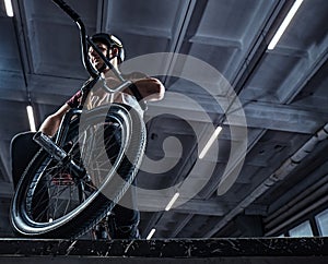 Teenage BMX rider sitting on his bicycle in a skatepark indoors