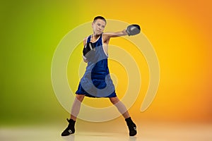 Teenage boxer against gradient neon studio background in motion of kicking, boxing