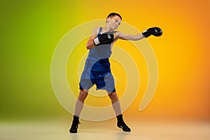 Teenage boxer against gradient neon studio background in motion of kicking, boxing