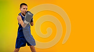 Teenage boxer against gradient neon studio background in motion of kicking, boxing