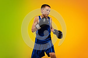 Teenage boxer against gradient neon studio background in motion of kicking, boxing