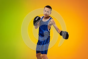 Teenage boxer against gradient neon studio background in motion of kicking, boxing