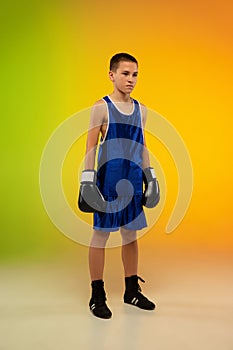 Teenage boxer against gradient neon studio background in motion of kicking, boxing