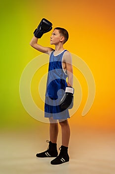Teenage boxer against gradient neon studio background in motion of kicking, boxing