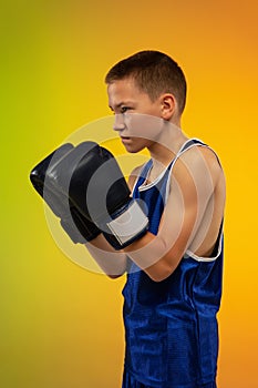 Teenage boxer against gradient neon studio background in motion of kicking, boxing