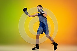 Teenage boxer against gradient neon studio background in motion of kicking, boxing