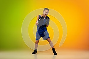 Teenage boxer against gradient neon studio background in motion of kicking, boxing