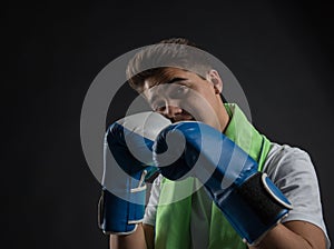 Teenage boxer posing with blue and white boxing gloves in a photographic studio