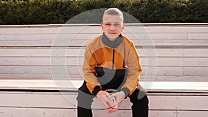 Teenage boy in anorak jacket sitting on street