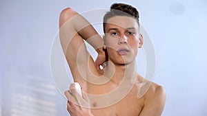 Teenage boy applying roll antiperspirant morning hygienic procedures puberty age