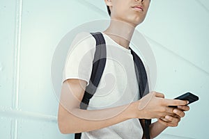 Teenage boy with backpack and cell phone outdoors. Teenager browse social media, communicate with friends, family, play