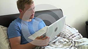 Teenage Boy In Bed Using Laptop Being Bullied Online