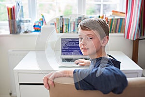 Teenage Boy In Bedroom Writing Computer Code