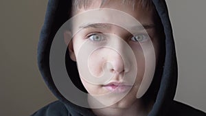 Teenage boy in black Hooded jacket looking directly to camera. Close up portret. 4k video