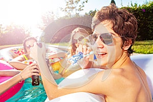 Happy boy with friends pool party blow noisemaker