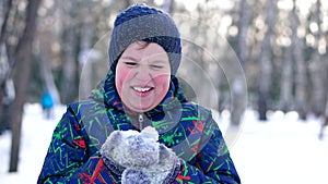 Teenage boy blowing snow from his hands.