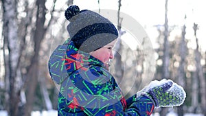 Teenage boy blowing snow from his hands.