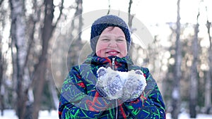 Teenage boy blowing snow from his hands.