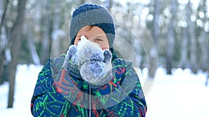 Teenage boy blowing snow from his hands.