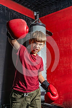 A teenage boy in boxing gloves angrily swings his fist for a blow photo