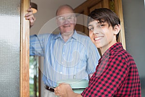 Teenage Boy Bringing Meal For Elderly Male Neighbour photo