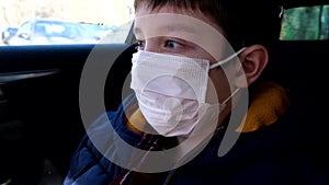 A teenage boy in a car wearing white surgical medical face mask as a protection against virus disease, coronavirus protection and