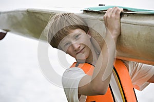 Teenage Boy Carrying Kayak