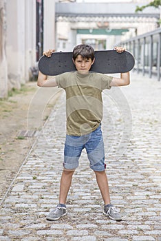 A teenage boy carrying skateboard and smiling