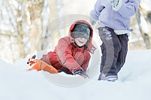 Teenage boy chasing after his sibling sister outdoors on snow hill