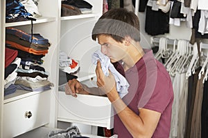 Teenage Boy Checking Freshness Of Clothes In Wardrobe