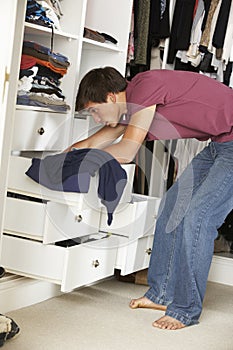 Teenage Boy Choosing Clothes From Wardrobe In Bedroom