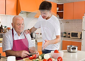 Teenage boy cooking with grandfather