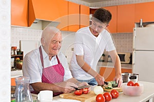 Teenage boy cooking with grandfather