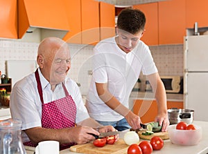 Teenage boy cooking with grandfather