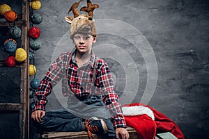 Teenage boy dressed in a plaid shirt and a hat with Christmas deer`s horns.
