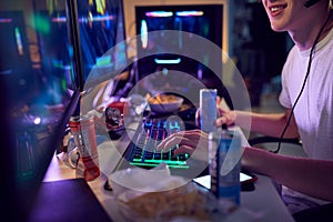 Teenage Boy Drinking Caffeine Energy Drink Gaming At Home Using Dual Computer Screens At Night