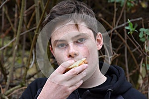 Teenage boy eats cheese sandwich