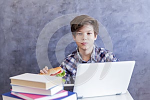 Teenage boy eats a sandwich and web-surfing