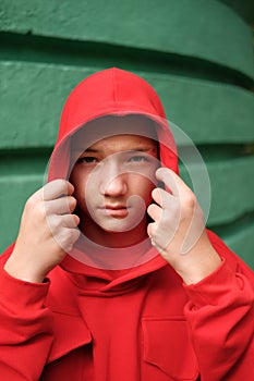 Teenage boy in fashionable hoodie against wall