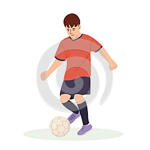 Teenage boy football player, in a red sports shirt, kicks a soccer ball. Kid sportsman playing football game, dynamic
