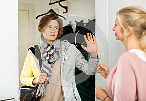 Teenage boy gesturing goodbye to mother while leaving home