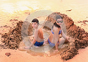 Teenage boy and girl play with sand on the beach