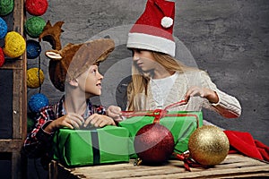 Teenage boy and a girl in Santa`s hat posing with gift boxes.