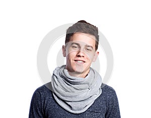 Teenage boy in gray sweater and scarf. Studio shot, isolated.
