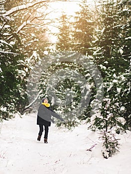 Teenage boy have fun and plays with snow in the winter forest. Clothes in color 2021